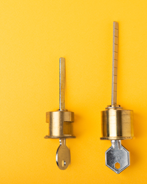 lock cylinders and keys next to each other on yellow background 